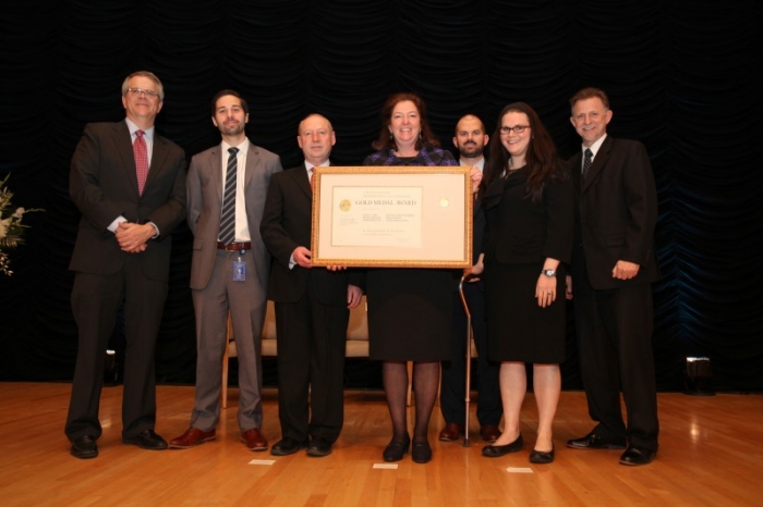 The OIG team holding their medal aside Deputy Secretary Andrews.