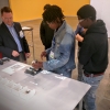 Dan Hartman (left) shows Chicago students how to assemble parts via video projection equipment