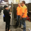 Secretary Penny Pritzker (left) speaks to two high school students (right) in a manufacturing plant