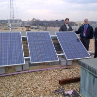 Officials atop the HCHB with solar panels