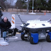 Visitors watch a Rutgers bridge repair robot go through its paces at a NIST meeting